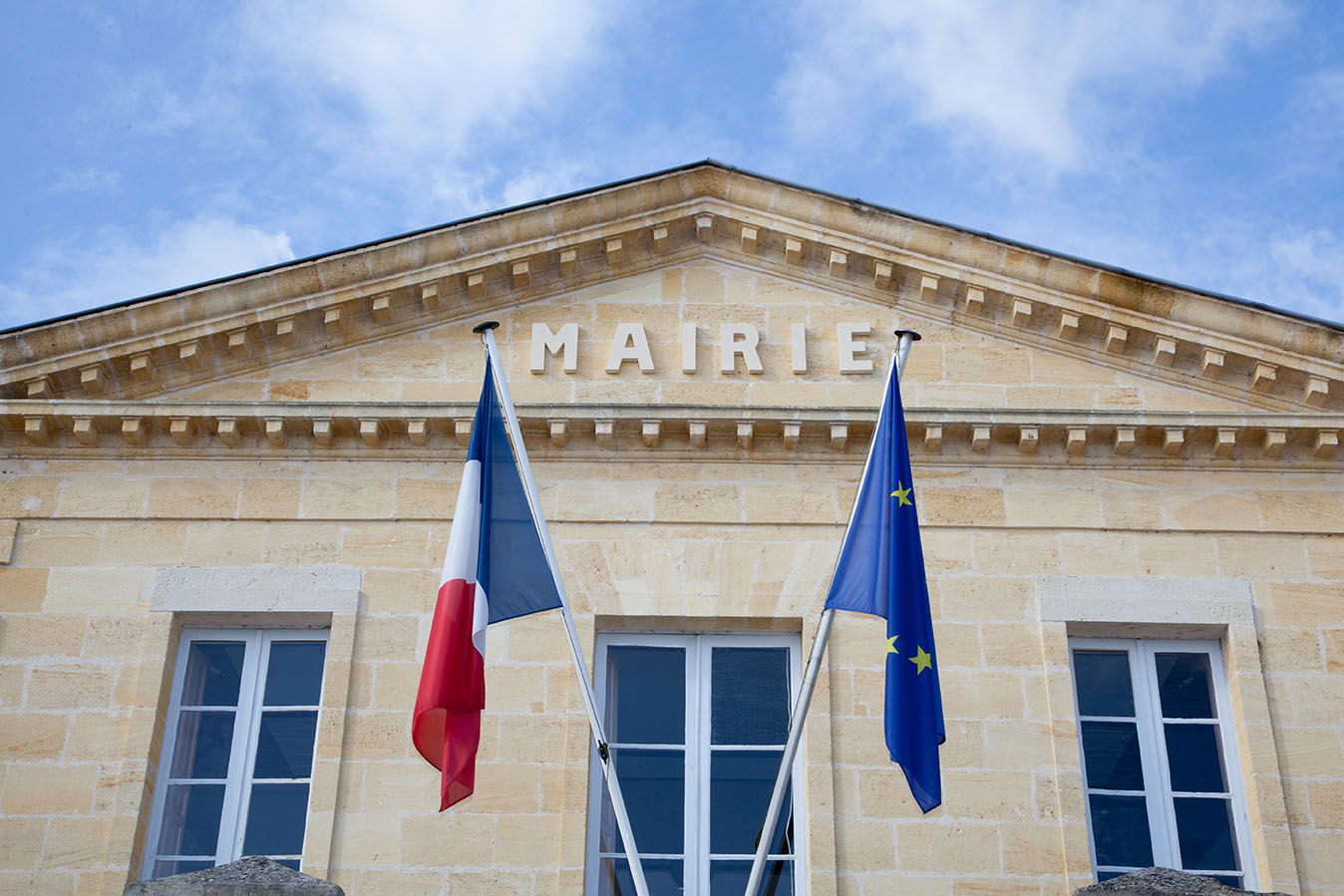 Façade d'une mairie française avec les drapeaux français et européen